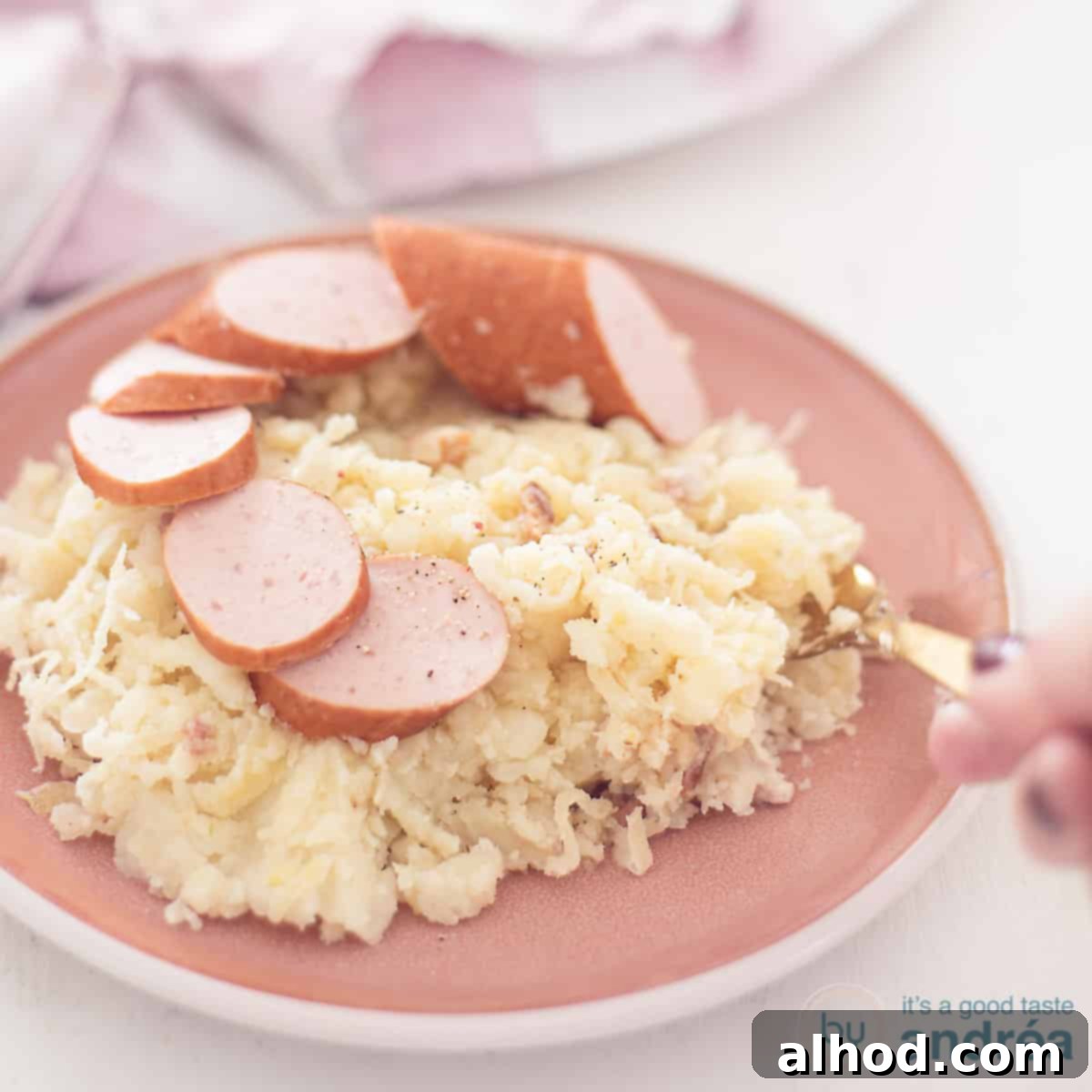 Hearty Dutch Sauerkraut Potato Mash 4 A square photo with a pink plate with sauerkraut stew with smoked sausage