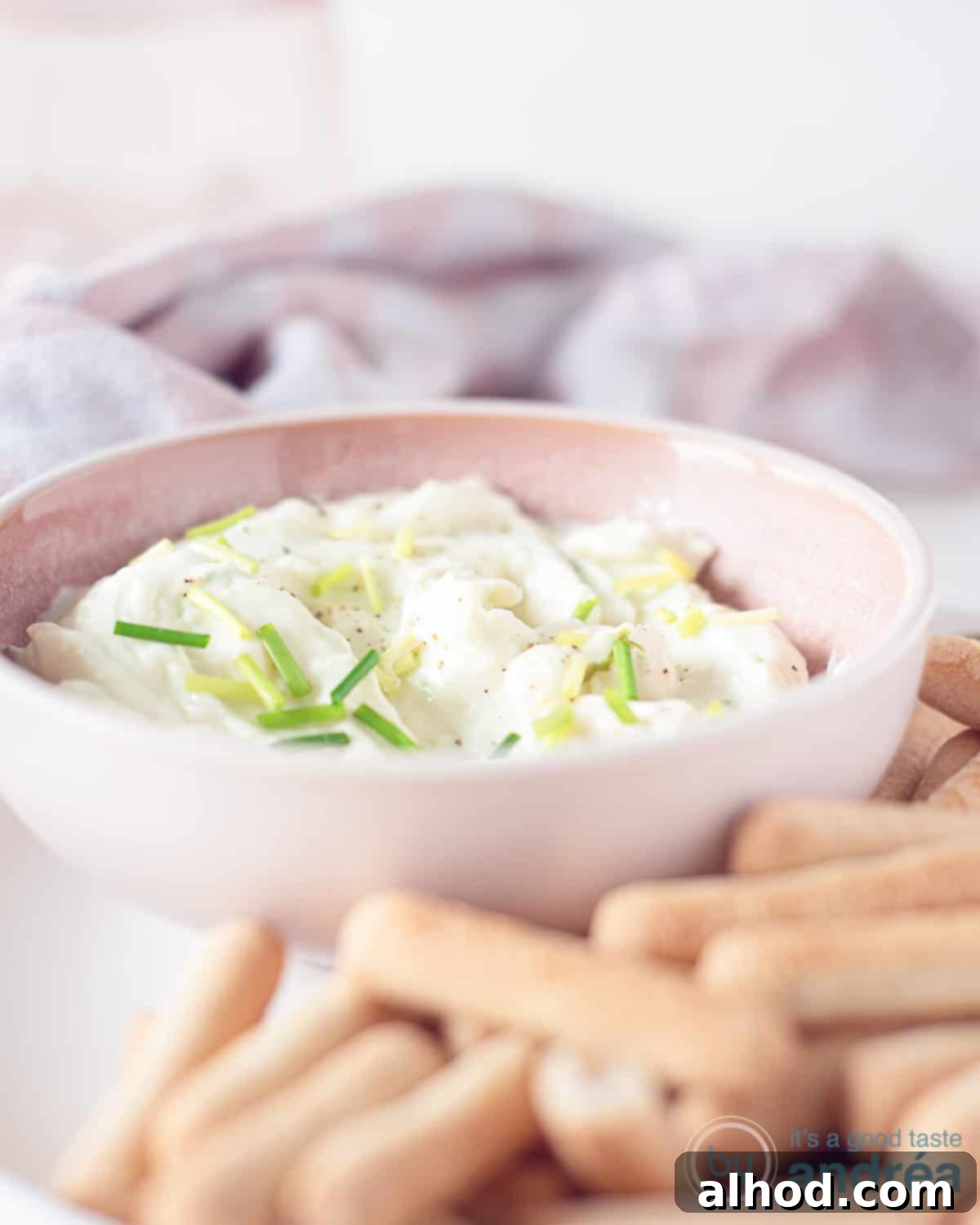 Creamy Gorgonzola Delight 2 A pink bowl with sticks in front of it and a pink and white tea towel behind it.