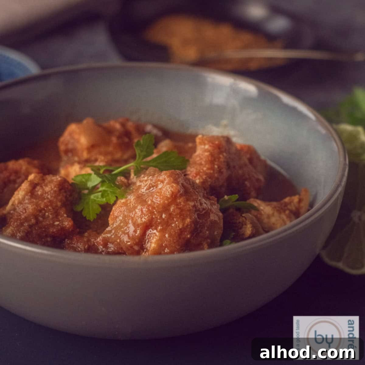 Crockpot Creamy Coconut Chicken Curry 4 A square photo with a pink bowl filled with chicken curry with coconut and delicious herbs. A white background.