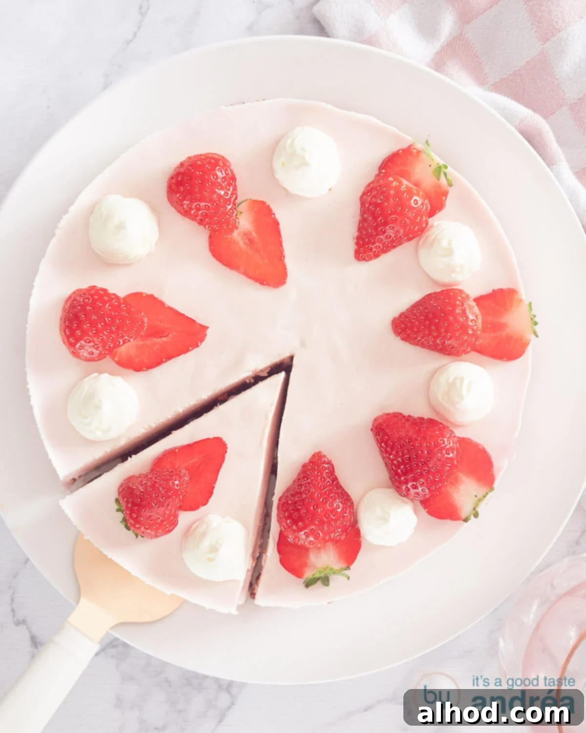 Strawberry Quark Cheesecake 2 A top-down view of a freshly made no-bake strawberry quark cheesecake with a slice cut out, showcasing its creamy pink filling and crumbly biscuit base, garnished with fresh strawberries.