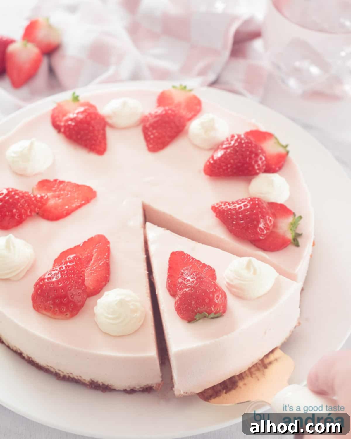 Strawberry Quark Cheesecake 3 A close-up side view of a strawberry quark cheesecake, showing its distinct layers of creamy filling and a thick Speculoos biscuit base, on a white plate with a gold cake server scooping a slice.