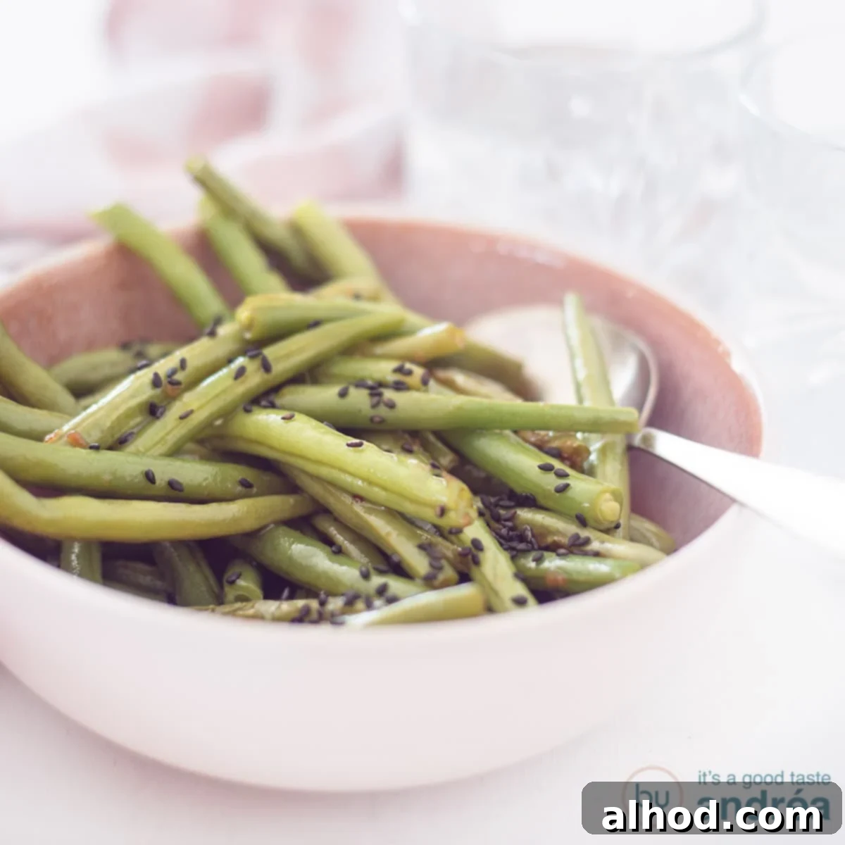 Sesame Garlic Green Beans 4 A square picture featuring a pink bowl overflowing with vibrant Asian-style stir-fried green beans, perfectly coated in a glossy sauce and ready to be served as a delightful side dish.