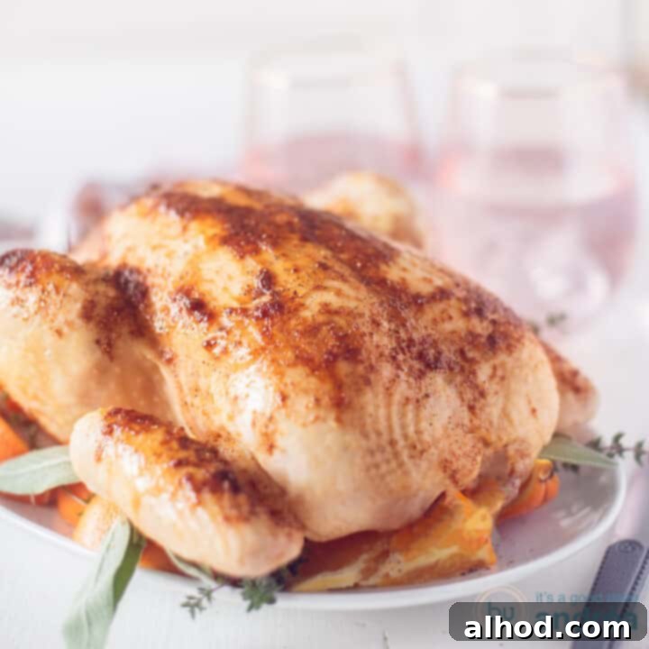 A square photo showing a roasted chicken with orange and honey glaze on a white plate