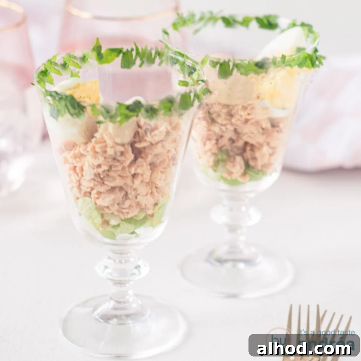 Chilled Dutch Salmon Delicacy 4 A square photo with two cocktail glasses filled with salmon, whiskey sauce and an egg. The rim of the glass at the top is garnished with parsley.