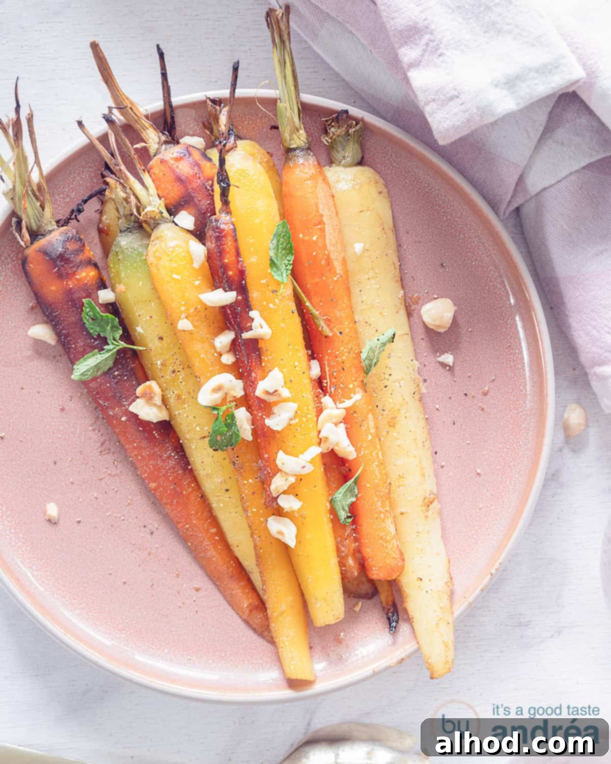 Masala Honey Roasted Carrots 2 A photo from above with roasted carrots in a honey carrot marinade with garam masala on a pink plate. A white background.