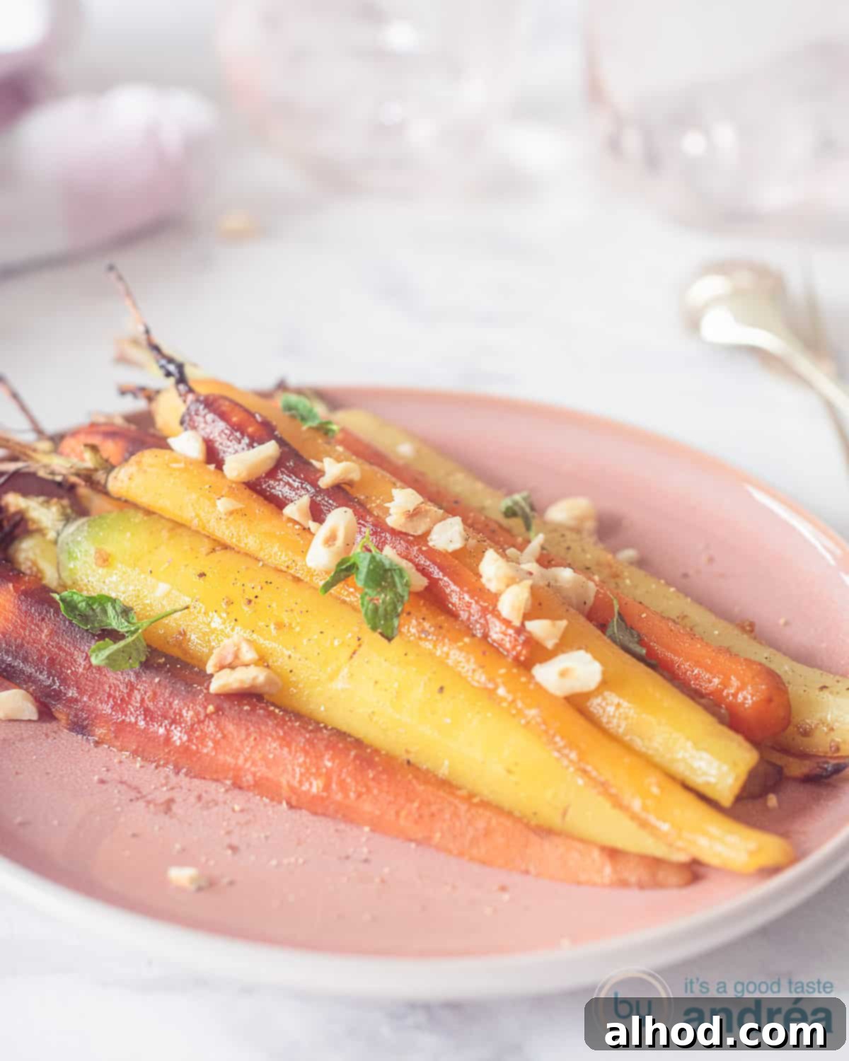 Masala Honey Roasted Carrots 3 A pink plate with colored rainbow carrots, roasted on a white background.