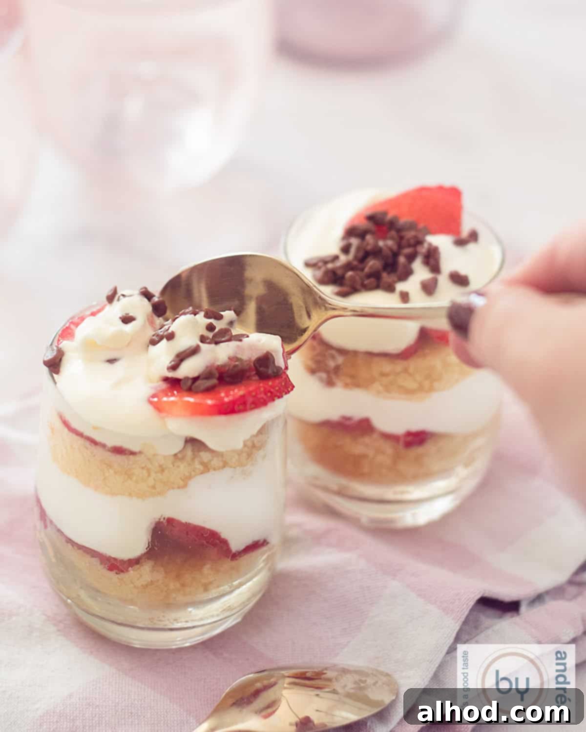 Strawberry Pound Cake Mini Trifles 3 Two glasses filled with strawberry mascarpone cream and cake trifles. A golden spoon takes a bite.