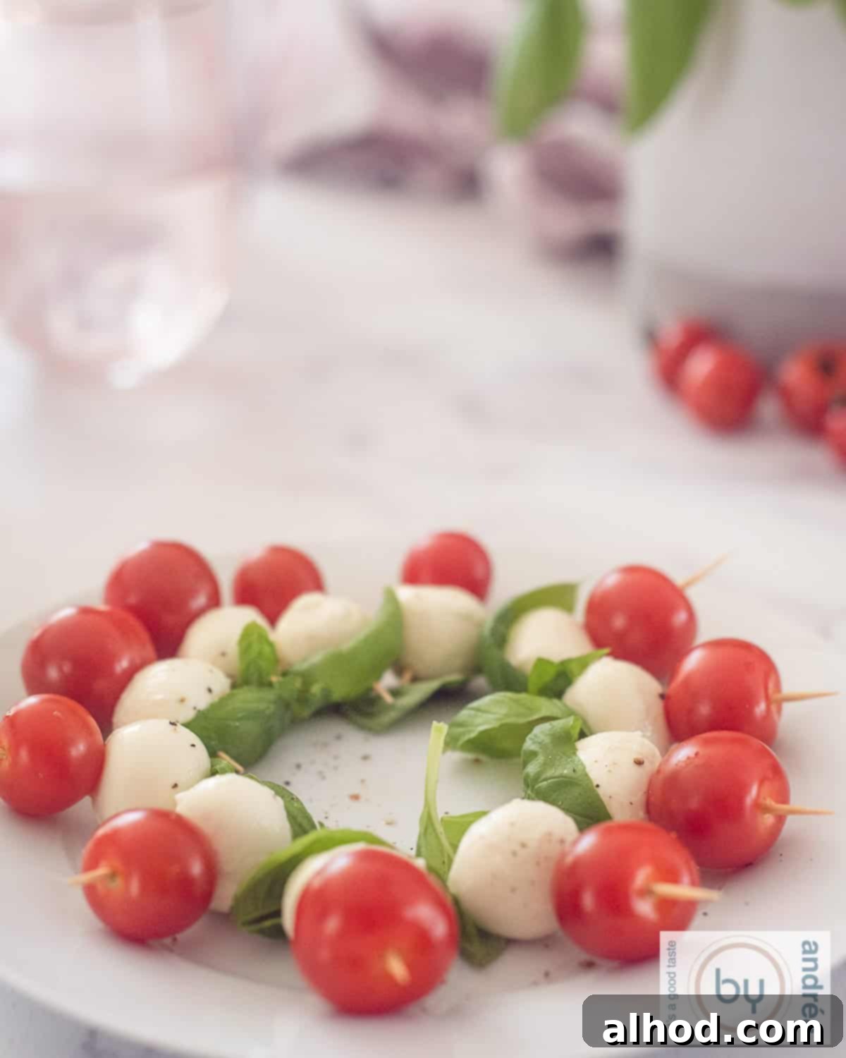 An overhead shot of a white rectangular platter brimming with mini Caprese salad skewers, each featuring a vibrant cherry tomato, a pristine mini mozzarella ball, and a verdant basil leaf, elegantly arranged for a party. The image highlights the fresh colors and simple beauty of these Italian appetizers.