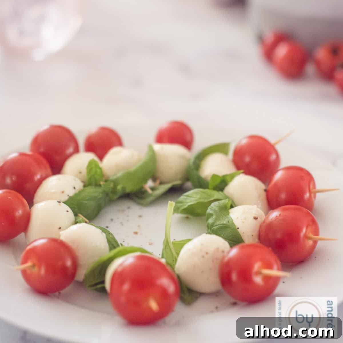 A close-up square shot of a bowl brimming with freshly assembled mini Caprese skewers.