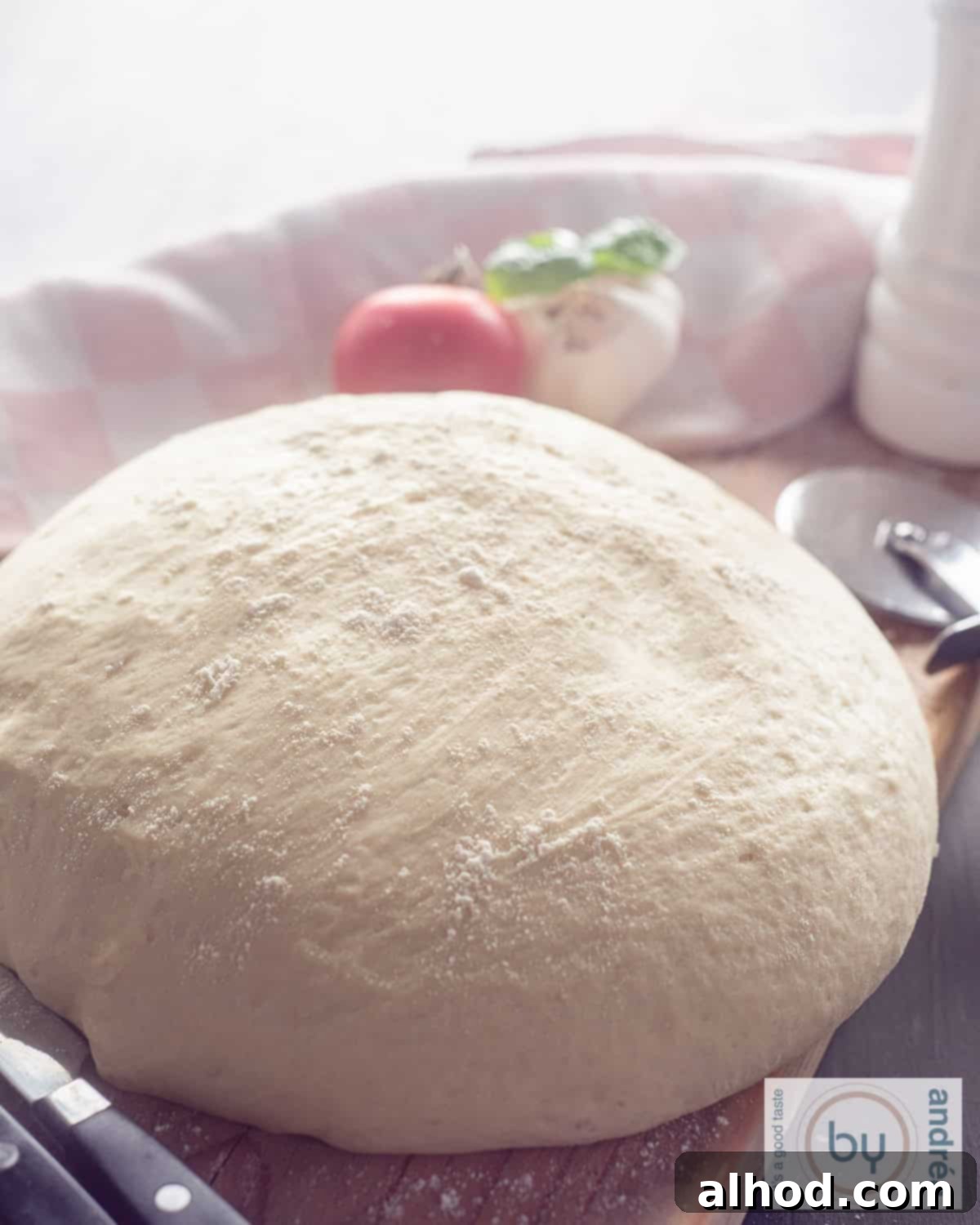Effortless Homemade Pizza Dough 5 A beautifully risen, airy ball of homemade pizza dough resting on a rustic wooden board, ready for rolling out. The dough looks perfectly proofed and elastic.