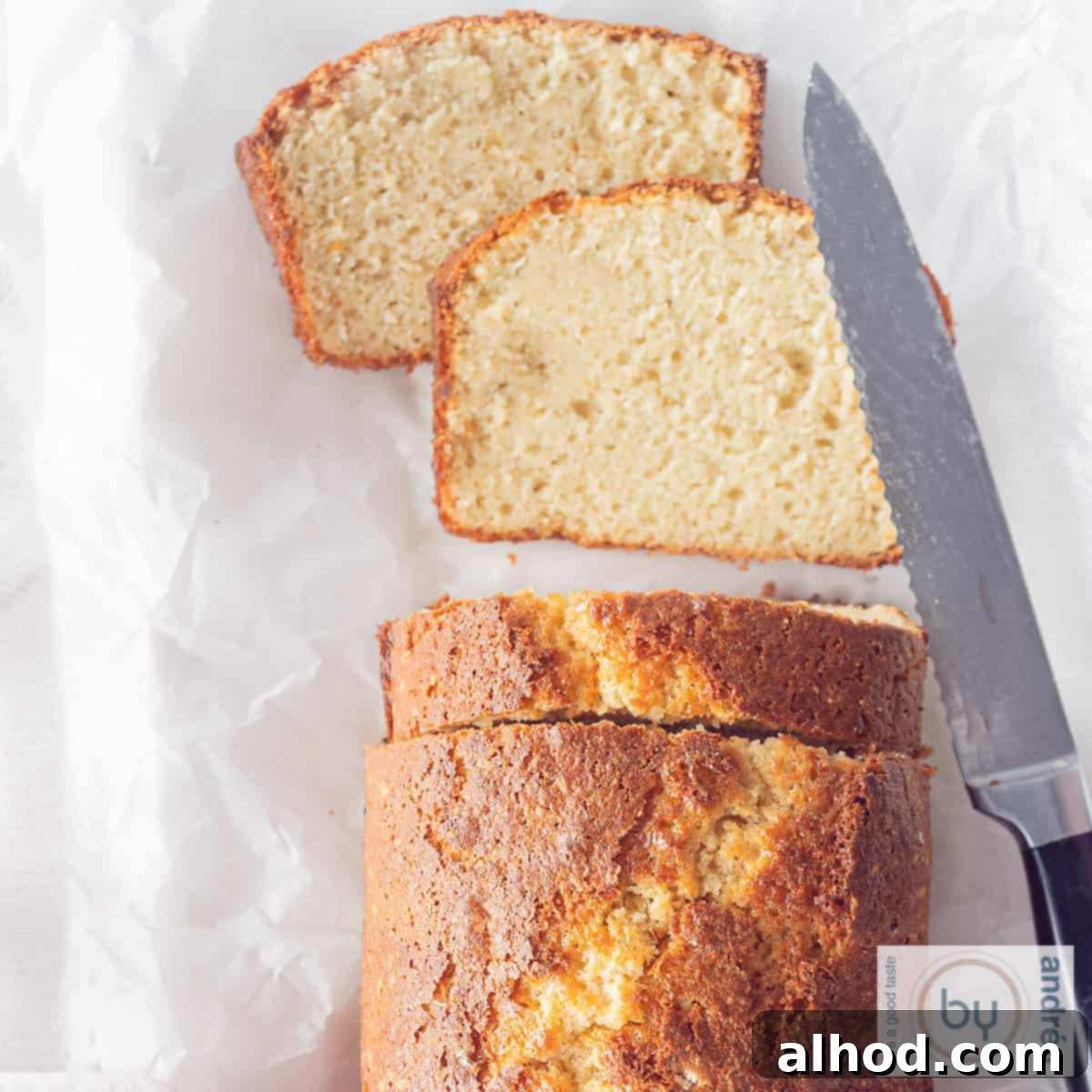 Effortlessly Light and Fluffy Vanilla Applesauce Cake 6 A square photo of an applesauce cake with two slices cut off and lying flat. A knife is next to it.
