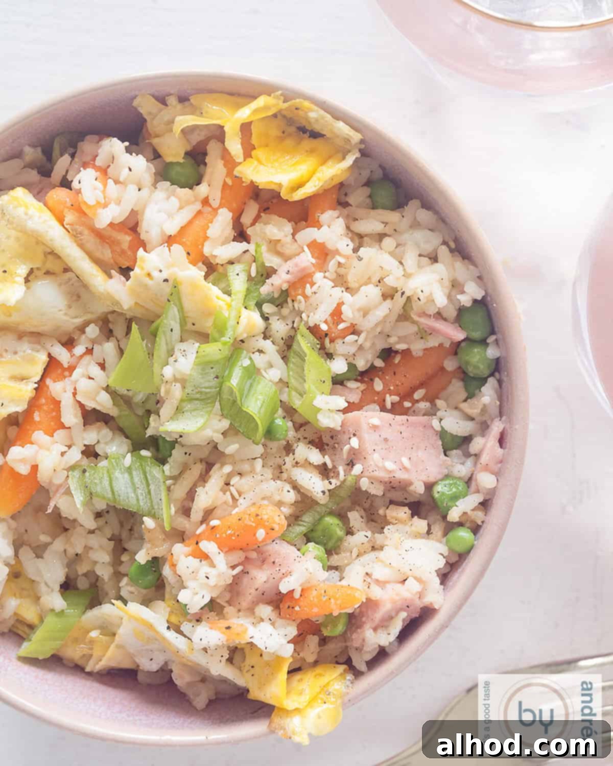 Speedy Ham, Egg, and Vegetable Fried Rice 2 An aerial photo with a bowl filled with rice, ham, carrot, peas, egg and seasonings. All on a white background.