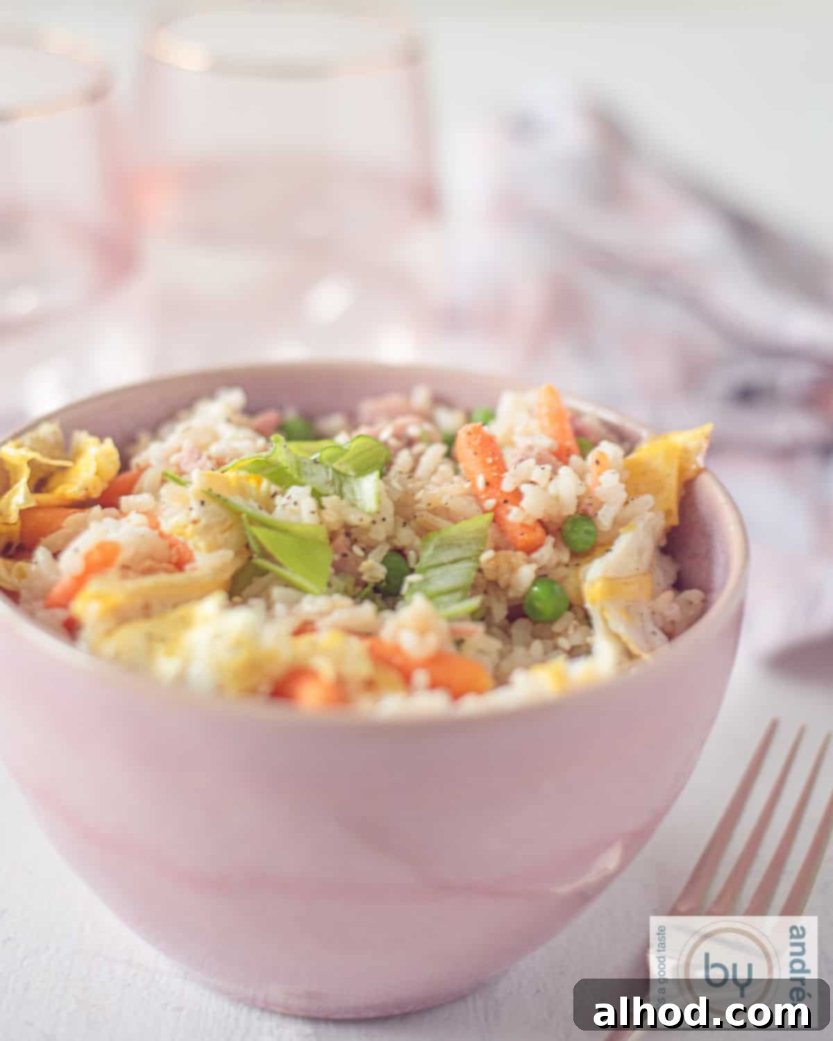 Speedy Ham, Egg, and Vegetable Fried Rice 5 An aerial photo with a bowl of fried rice, vegetables, ham and egg. A pink and white tea towel in the background