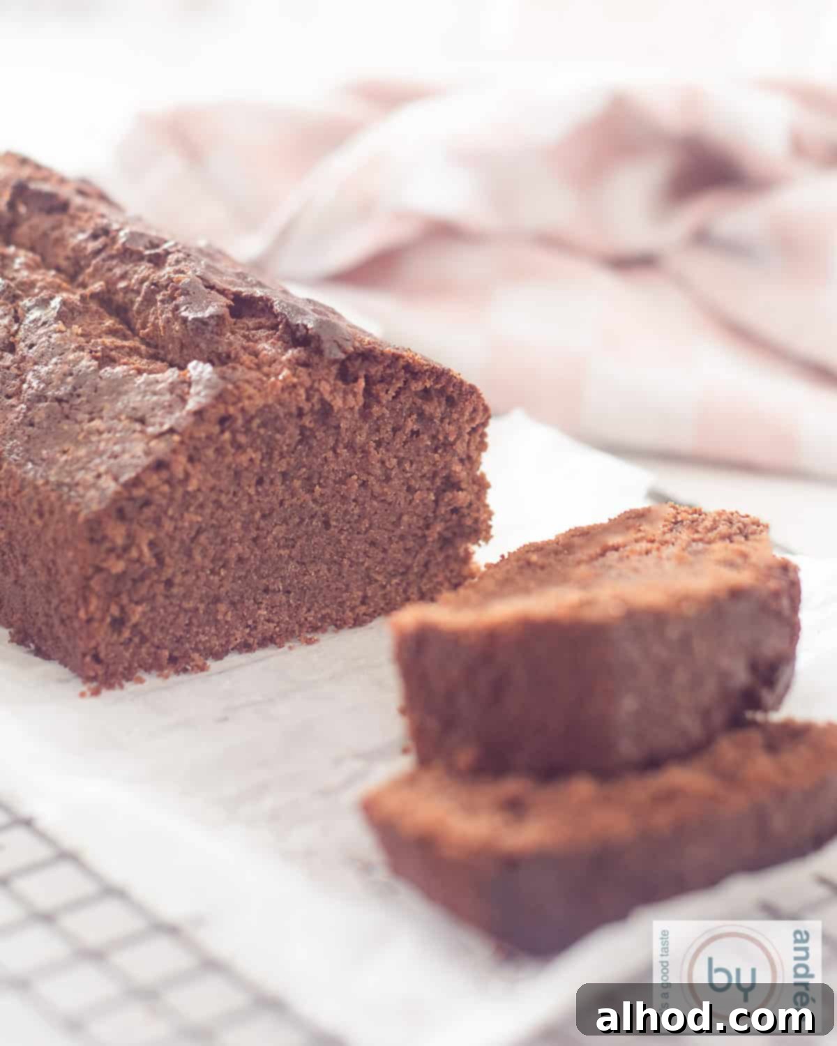 Vanilla-Infused Moist Chocolate Loaf Cake 2 An height photo of chocolate cake on a baking sheet on a rack from which two slices have been cut