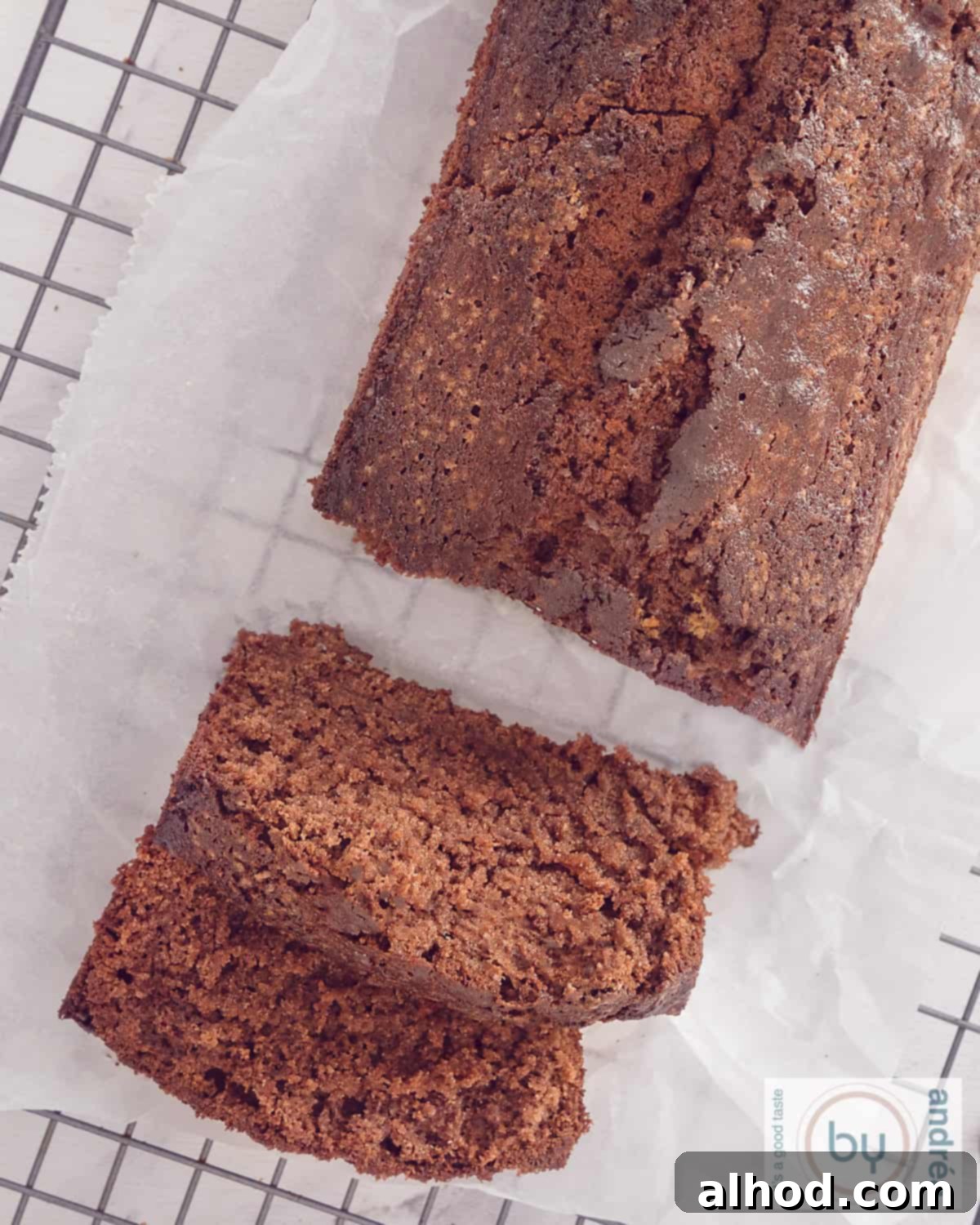 Vanilla-Infused Moist Chocolate Loaf Cake 5 A photo from above of a baking rack with a chocolate cake with cocoa from which two slices have been cut.