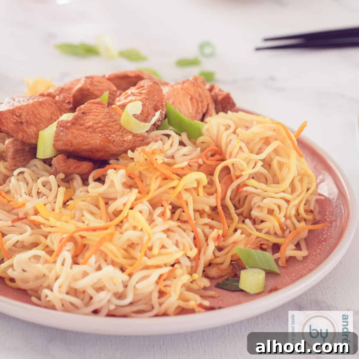 Cantonese Chicken with Egg Noodles Speedy Dinner 6 A square photo with a pink plate with noodles and cantonese chicken. A white background.