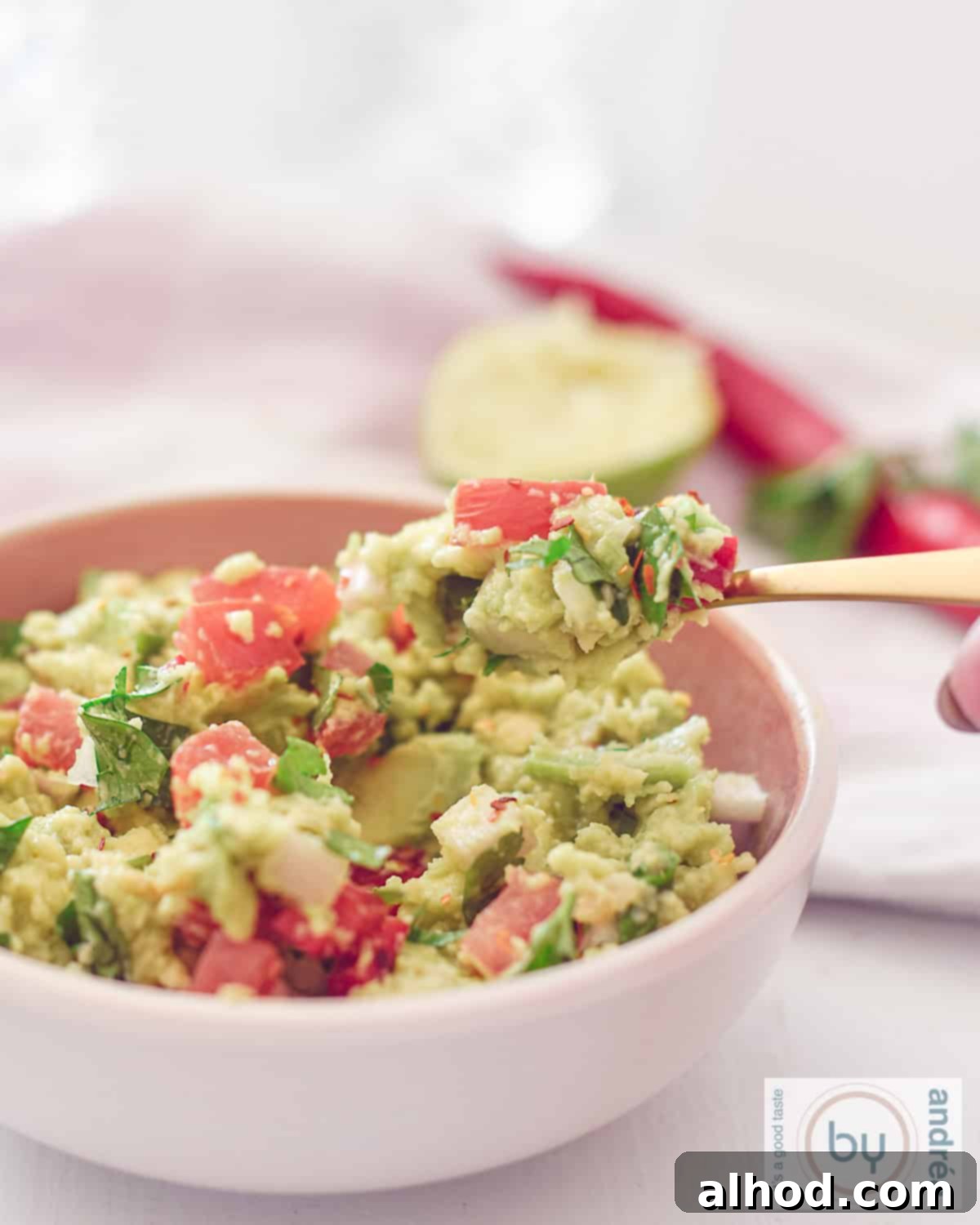 Creamy Avocado & Zesty Lime Guacamole The Perfect Dip 4 A height photo of a pink bowl filled with homemade guacamole, ready to be served.