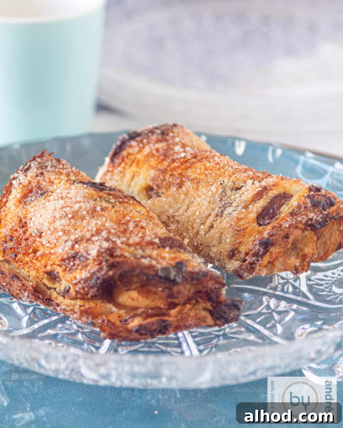 Cinnamon Apple French Toast Roll-Ups 4 A glass plate with two simple apple rolls on it. A blue mug in the background.