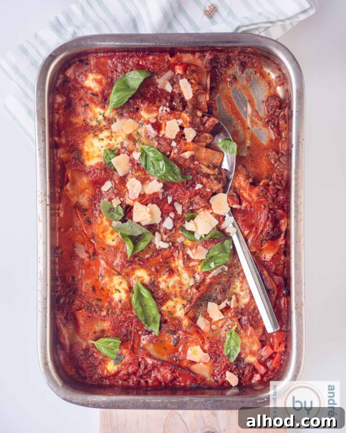 Decadent One Pot Bacon Mascarpone Lasagna 5 A photo from above of a roasting pan filled with lasagna with bacon, mozzarella, mascarpone and minced tomato sauce. Some of it has already been scooped out.