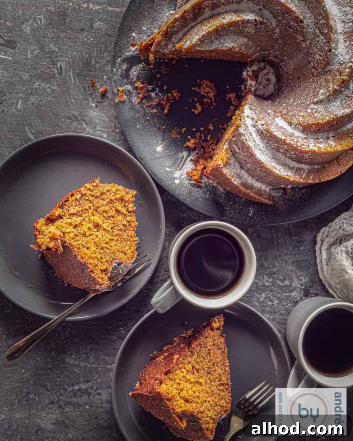 Harvest Spice Pumpkin Bundt Cake 5 A top-down photo of a pumpkin bundt cake with two pieces cut out of it and lying on a gray plate.
