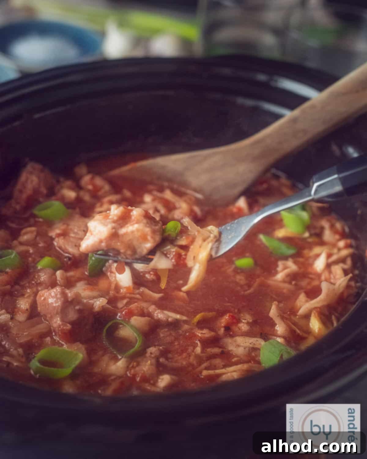 Homestyle Slow Cooker Ham and Cabbage Stew 2 A photo of part of a slow cooker filled with ham steak, cabbage and a rich sauce. A fork scoops some out of the slow cooker