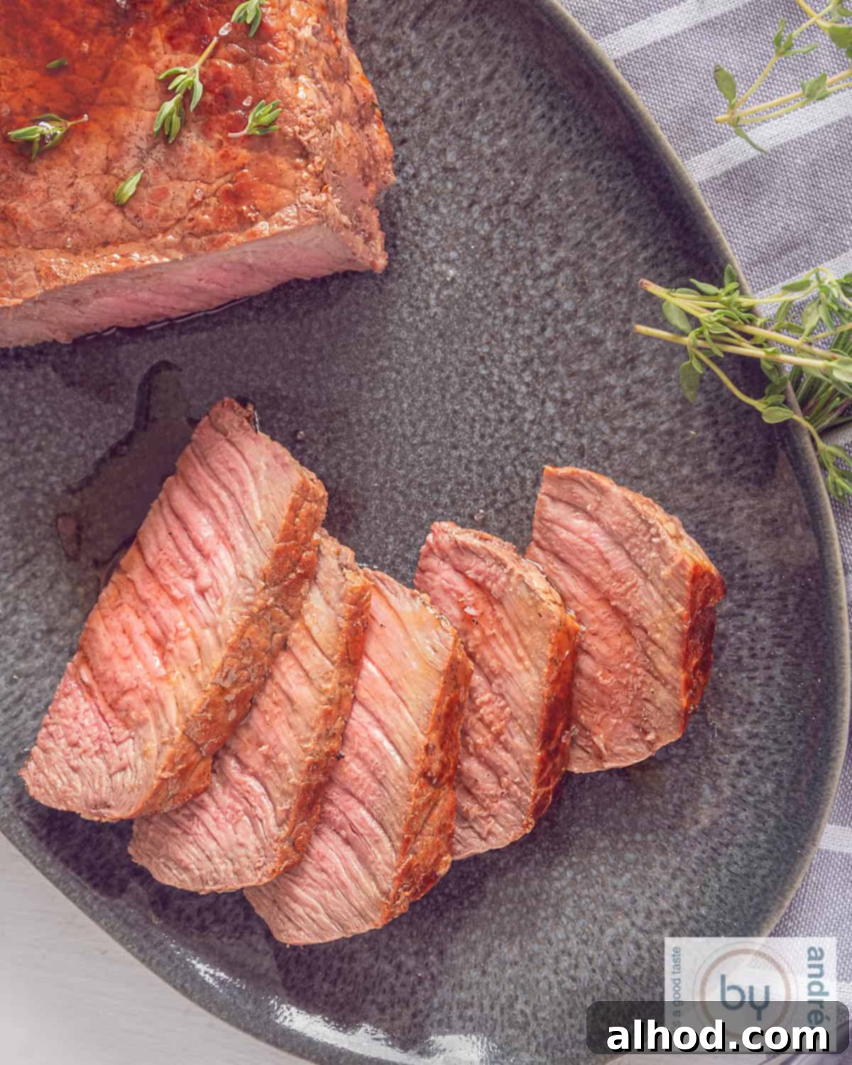 Succulent Roast Beef with Aromatic Herb Garlic Butter 5 A photo from above of a black platter of roast beef, sliced with herb butter