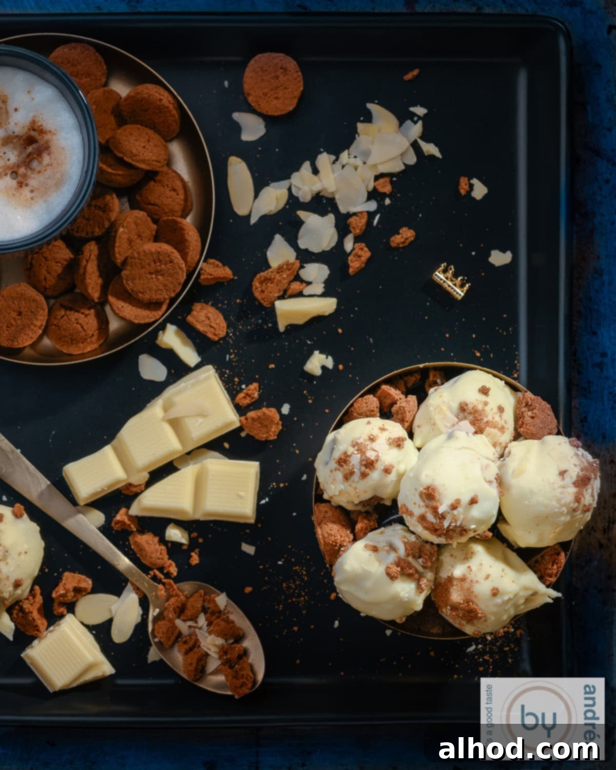 Decadent White Chocolate Pepernoten Truffles 2 A photo from above of a black background with a bowl of white chocolate pepernoten truffles, a bowl of gingerbread, white chocolate, and almond shavings