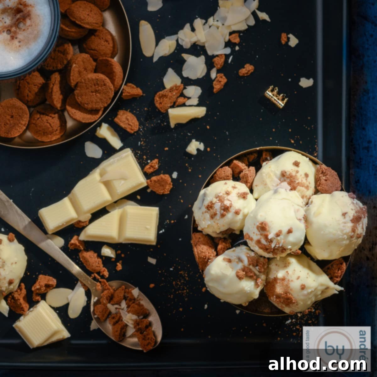 Decadent White Chocolate Pepernoten Truffles 6 A square photo of a black background with a bowl filled with gingerbread truffles with white chocolate, surrounded by kruidnoten, white chocolate, almond shavings and coffee.