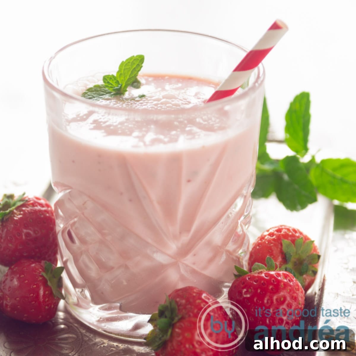8 Delicious and Healthy Smoothies to Kickstart Your Day 7 square photo with a glass filled with a strawberry orange yogurt smoothie, a red straw and surrounded with fresh strawberries and mint