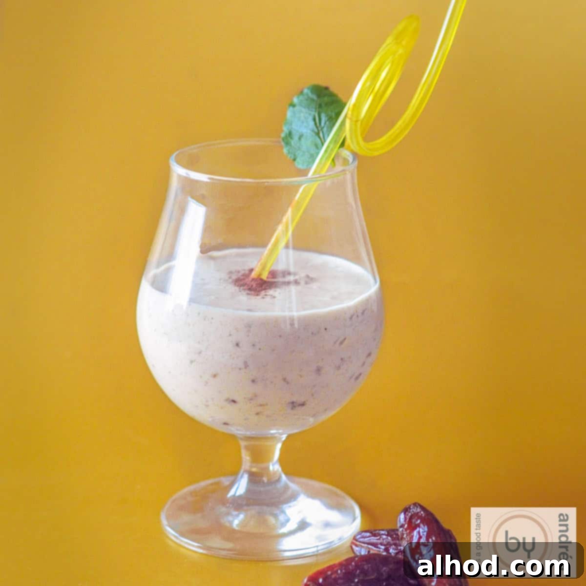 8 Delicious and Healthy Smoothies to Kickstart Your Day 8 A square photo with a yellow background. In the foreground a mango coconut smoothie with dates.