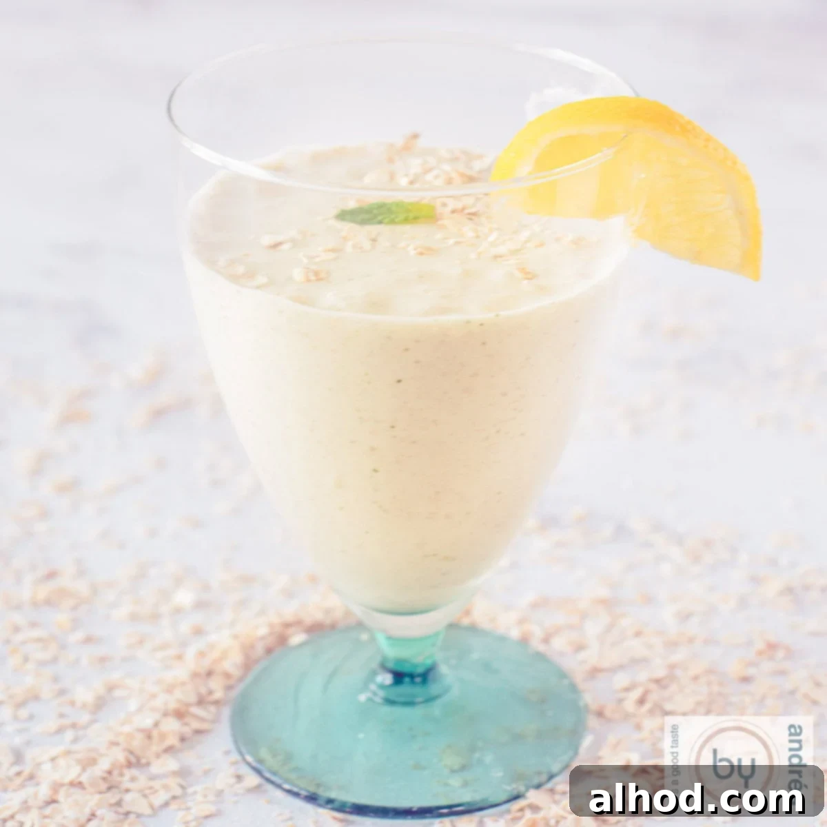 8 Delicious Smoothies to Power Your Healthy Morning 9 A square picture of a glass filled with a creamy banana oat smoothie, garnished with fresh mint, against a clean background.