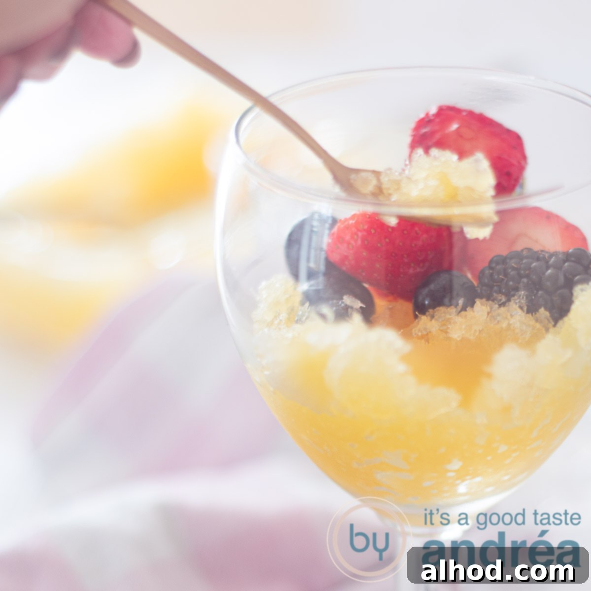 Father's Day Feast for Dad 7 A square photo featuring a glass partially filled with a vibrant orange beer sorbet, elegantly topped with fresh fruit and accompanied by a golden spoon.