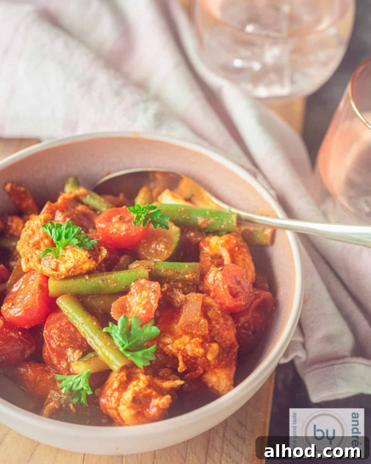 Whip Up Easy Chicken Jalfrezi: Dinner in Minutes 2 A vibrant pink bowl of homemade Chicken Jalfrezi, garnished with fresh cilantro and a side of basmati rice, set against a rustic background. The tender chicken and colorful vegetables are clearly visible in the spicy, rich sauce.