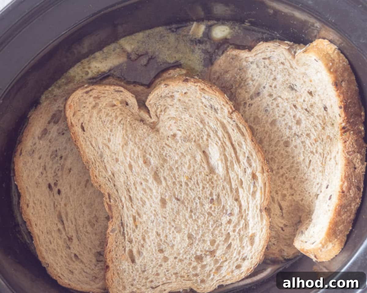 Melt-in-Your-Mouth Slow Cooker Dutch Sukadelapjes 6 A slow cooker with contents on which slices of bread have been placed.