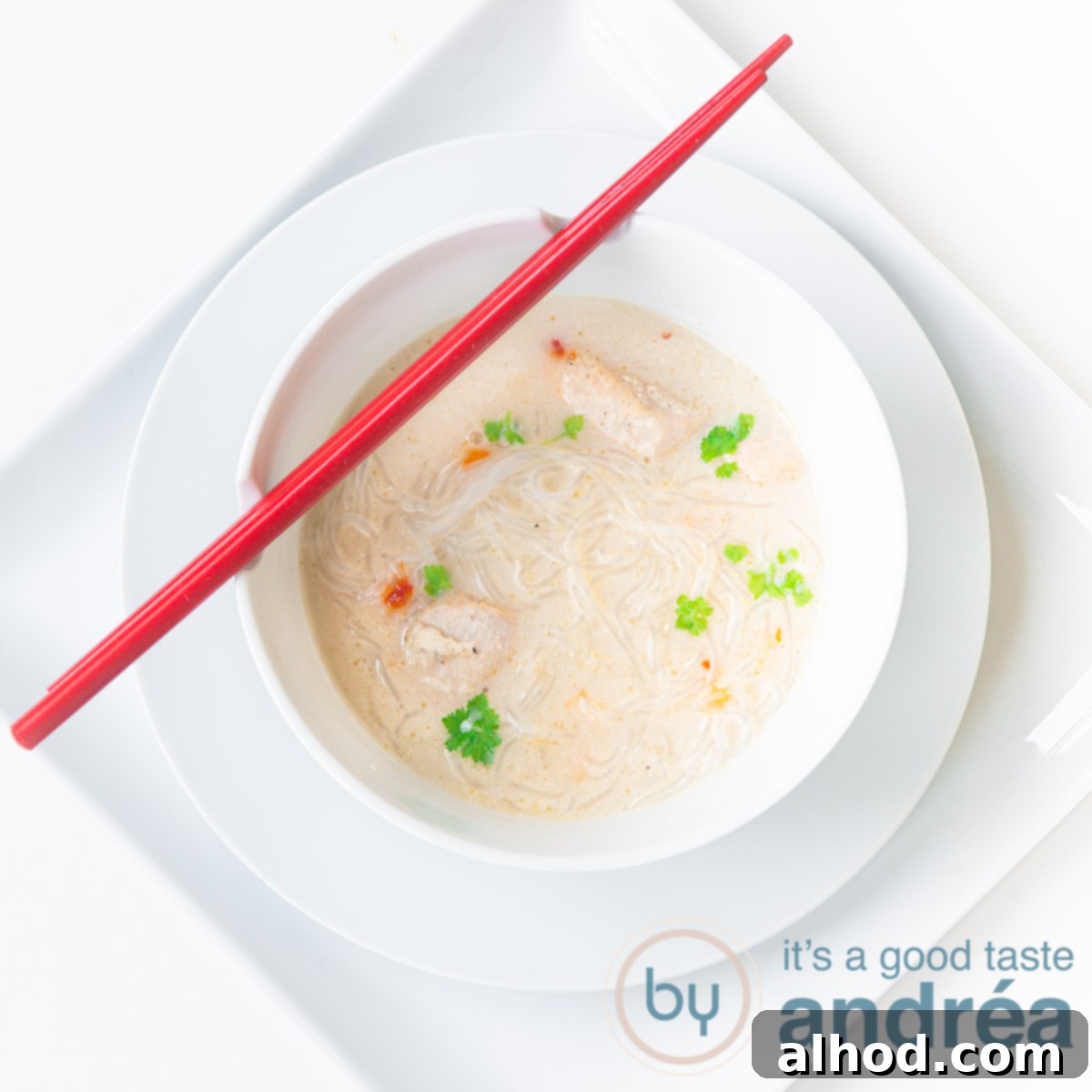 Taste Asia: Seven Soups You Can't Miss 4 A square photo with a white background, a square plate, a round plate and a white soup bowl filled with creamy chicken soup. Two red chopsticks lie on it.