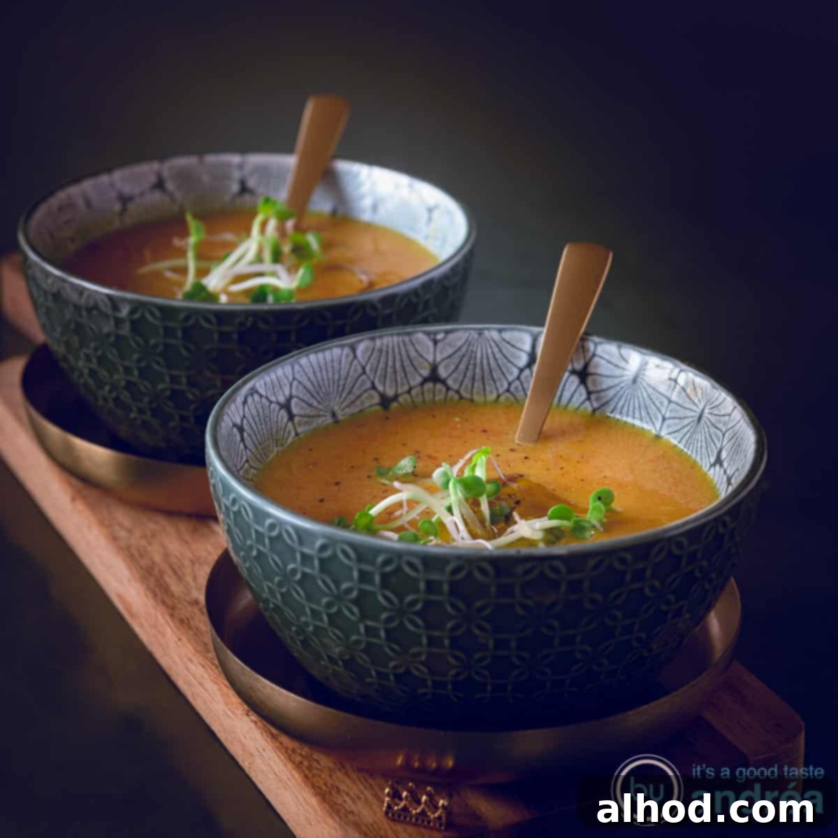 7 Incredible Asian Soups You Need to Taste 6 A square photo with two bowls on a gold platter on a wooden board. In the bowls Oriental pumpkin soup with cress.