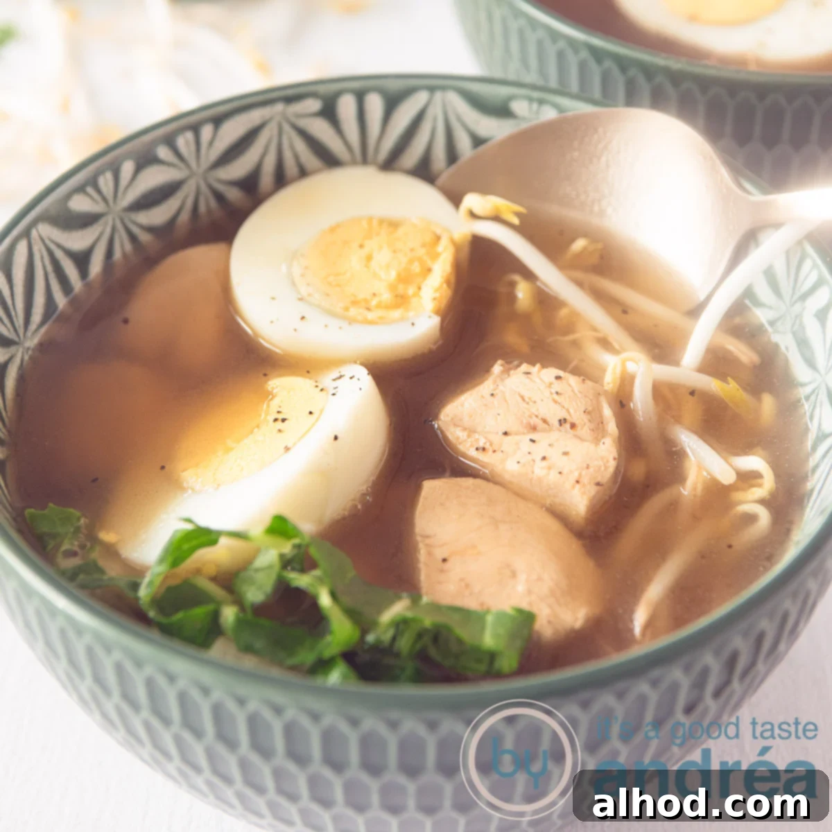 Taste Asia: Seven Soups You Can't Miss 8 A square photo of a green bowl filled with Japanese noodle soup with chicken, bok choy, bean sprouts and eggs. A golden spoon takes a bite.