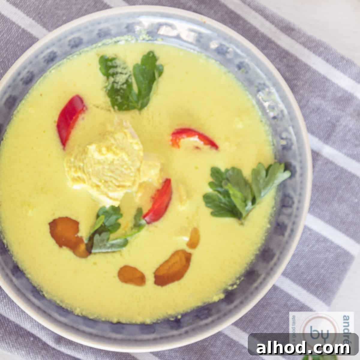 7 Incredible Asian Soups You Need to Taste 9 A square photo with a gray bowl filled with chicken soup with coconut milk, chicken and herbs.