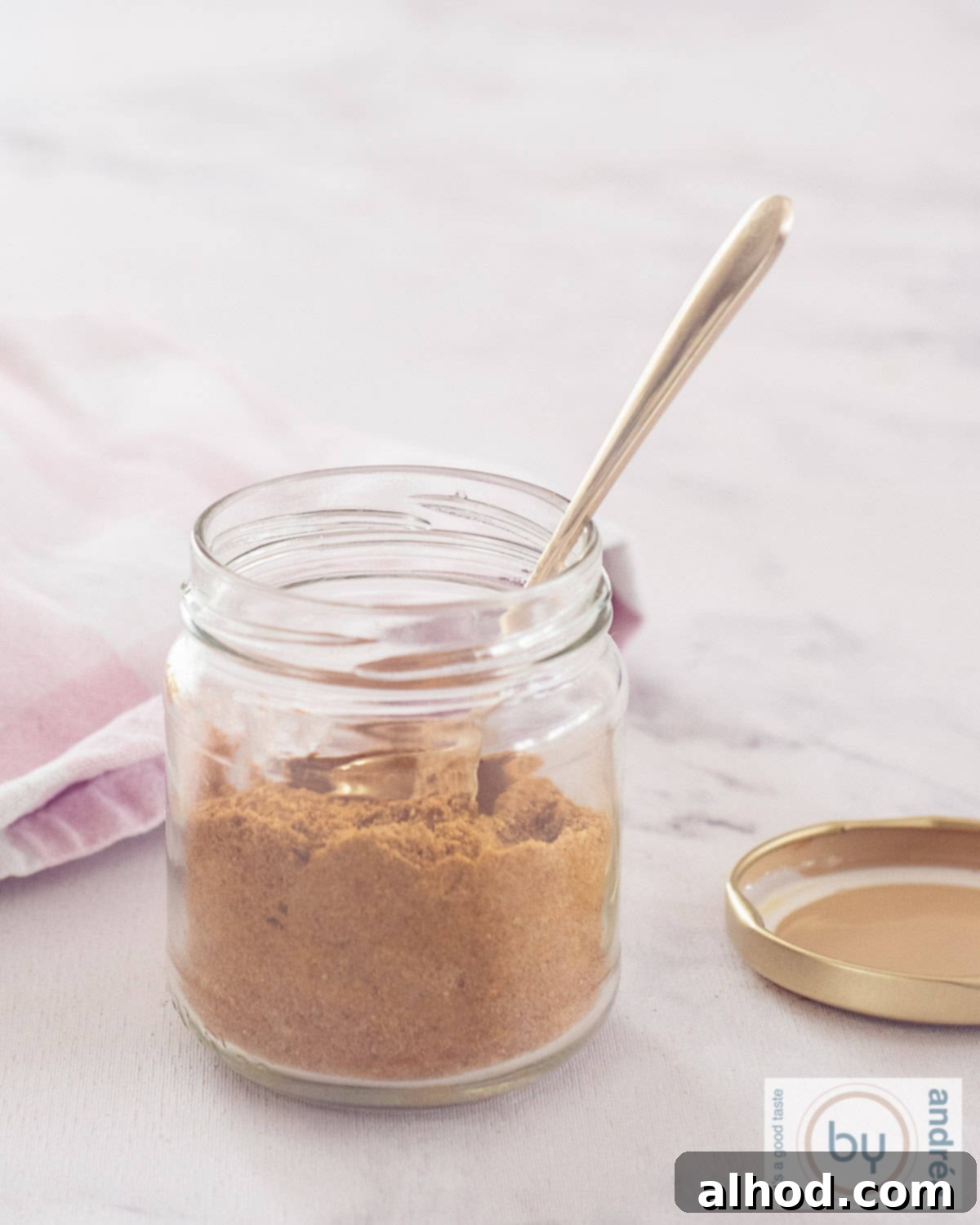 Authentic Homemade Madras Curry Blend 4 A tall, elegant photo showcasing a clear glass jar, proudly displaying the rich, reddish-brown Curry Madras spice mix within. A small spoon is nestled inside the jar, ready to scoop out the aromatic blend.