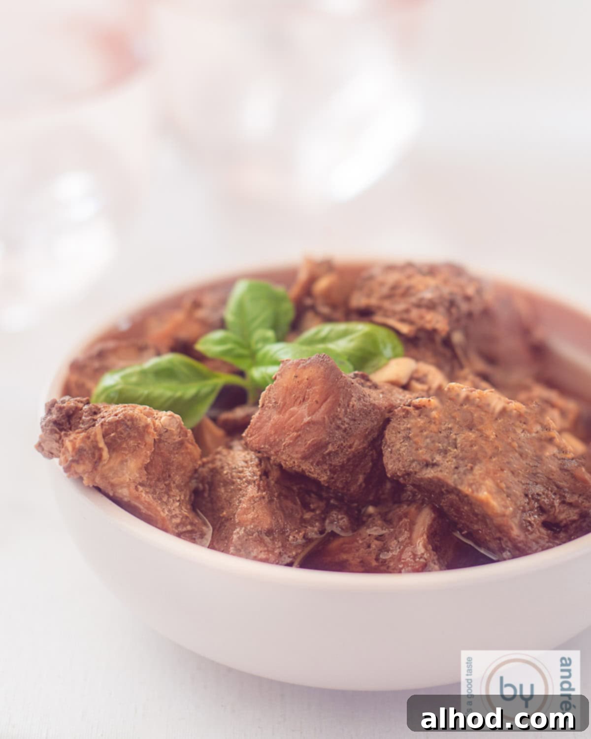 Peposo Tuscan Red Wine Beef Stew 8 A height photo of a pink bowl filled with peposo and a sprig of basil
