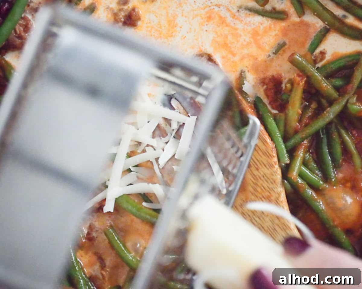 Parmesan cheese is grated over the penne alla vodka.