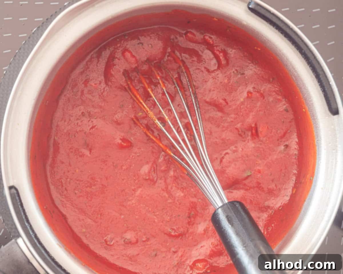 Ultimate Cheesy Beef Enchiladas with a Kick 5 A saucepan with simmering enchilada sauce, rich in color and texture.