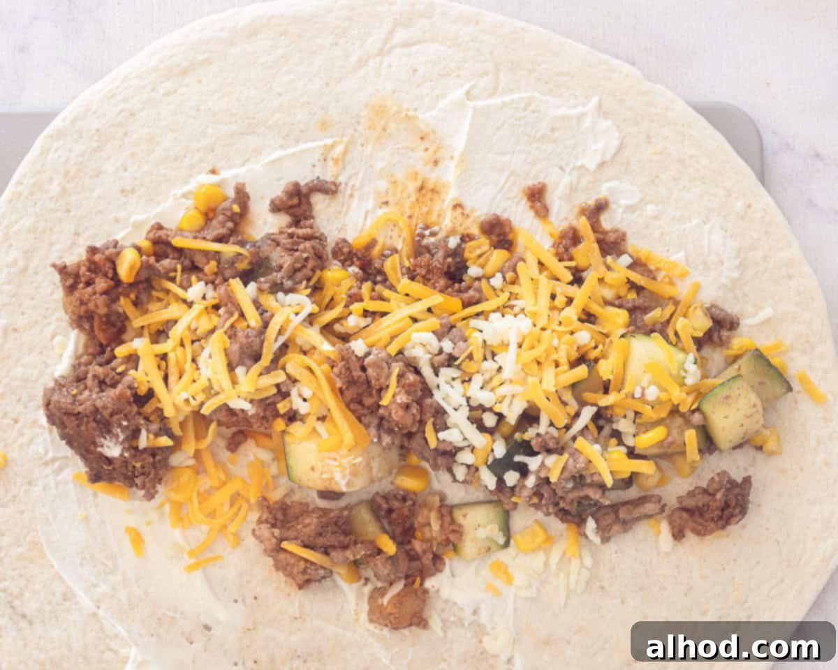 Ultimate Cheesy Beef Enchiladas with a Kick 7 A tortilla spread with a thin layer of sour cream, ready to be filled with the ground beef mixture and cheese before rolling.
