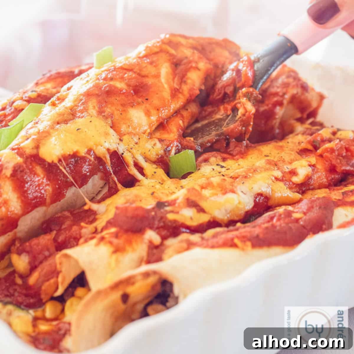 Ultimate Cheesy Beef Enchiladas with a Kick 10 A square photo of a white bowl with Mexican enchiladas filled with ground beef, corn, tomato sauce and cheese.