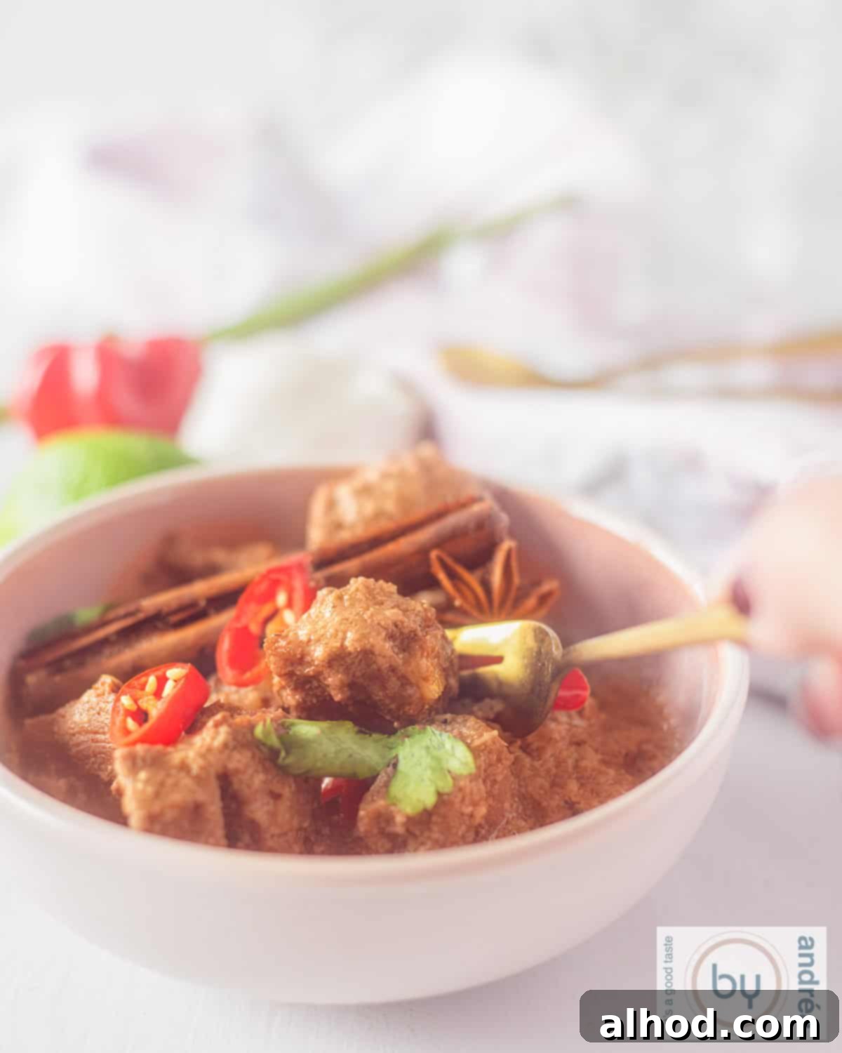 A height photo with beef rendang, parsley, chili pepper, cinnamon and star anise.