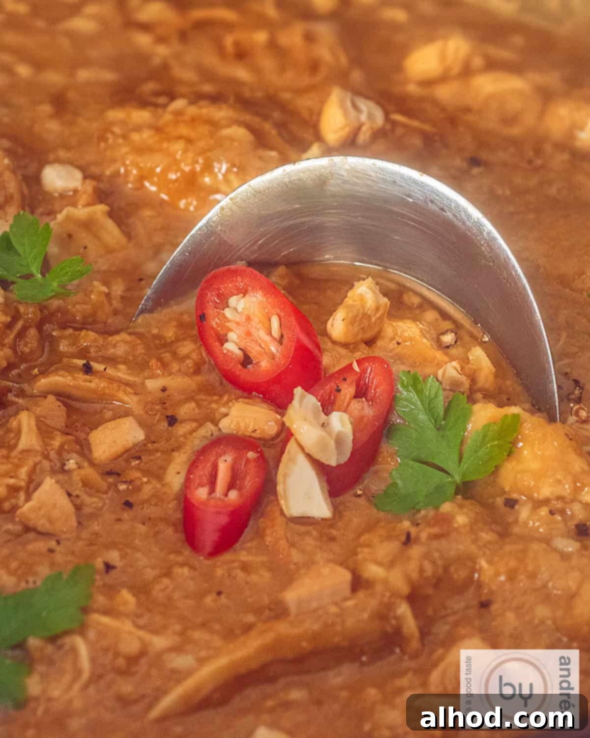 Creamy Slow Cooker Peanut Satay Chicken 3 Satay sauce with chicken, nuts and a garnish of chili pepper and parsley.