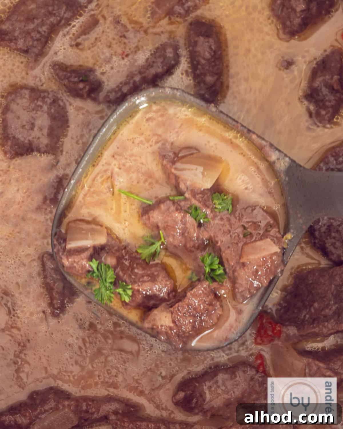 Beef Trinchado from which a soup spoon of stewed meat is scooped.