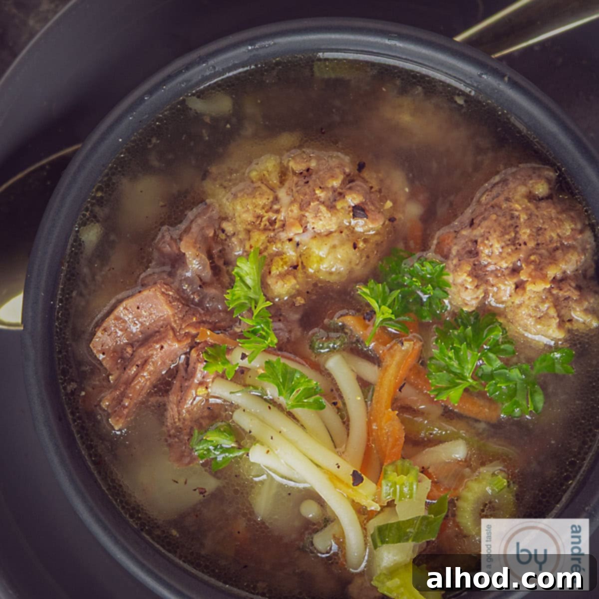 Hearty Dutch Meatball Vegetable Soup 4 A square photo from above of vegetable soup with meatballs, vegetables, vermicelli and parsley.