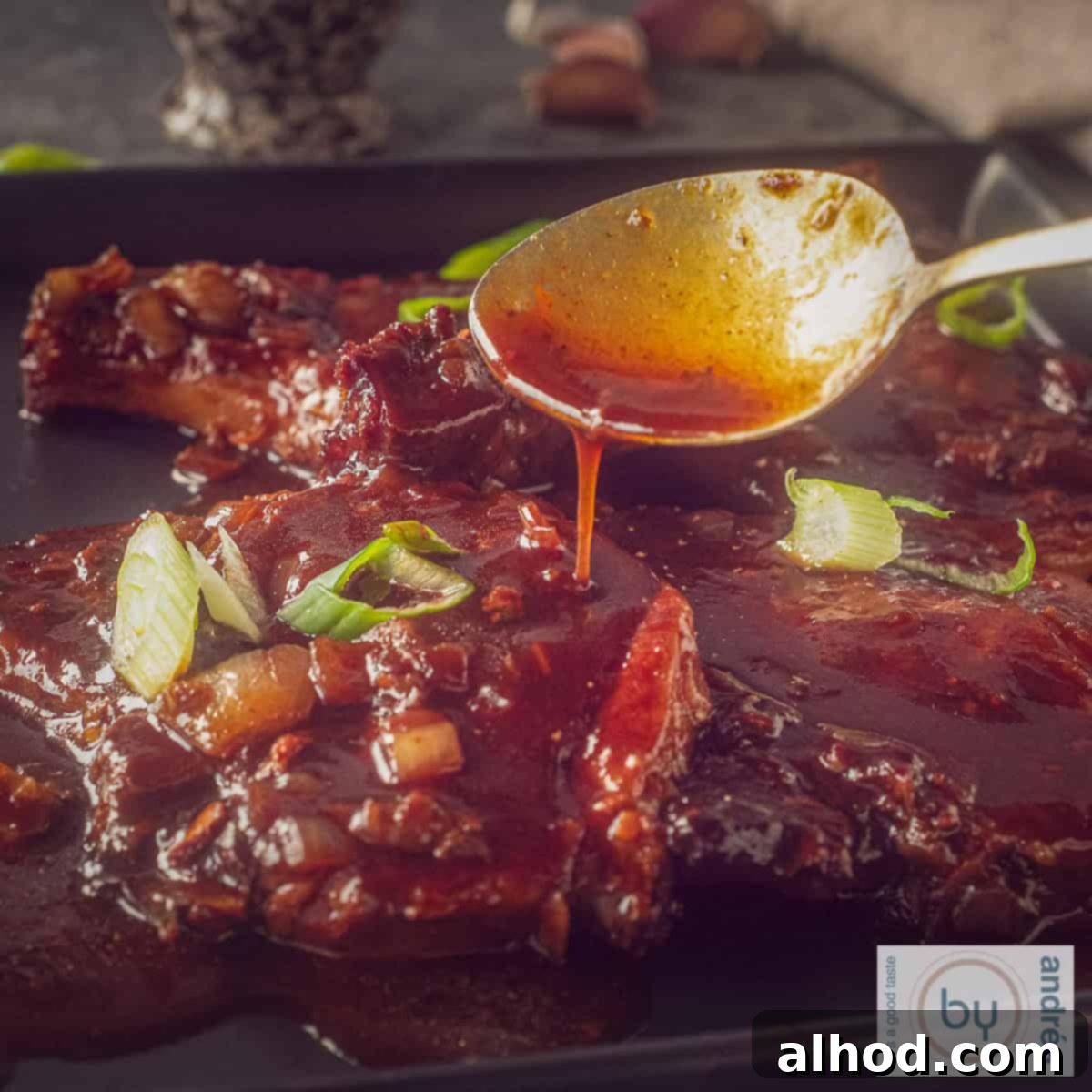 Caramelized Soy Pork Chops 4 A square photo of pork chops with soy sauce. A spoon of sauce drips onto the chops.