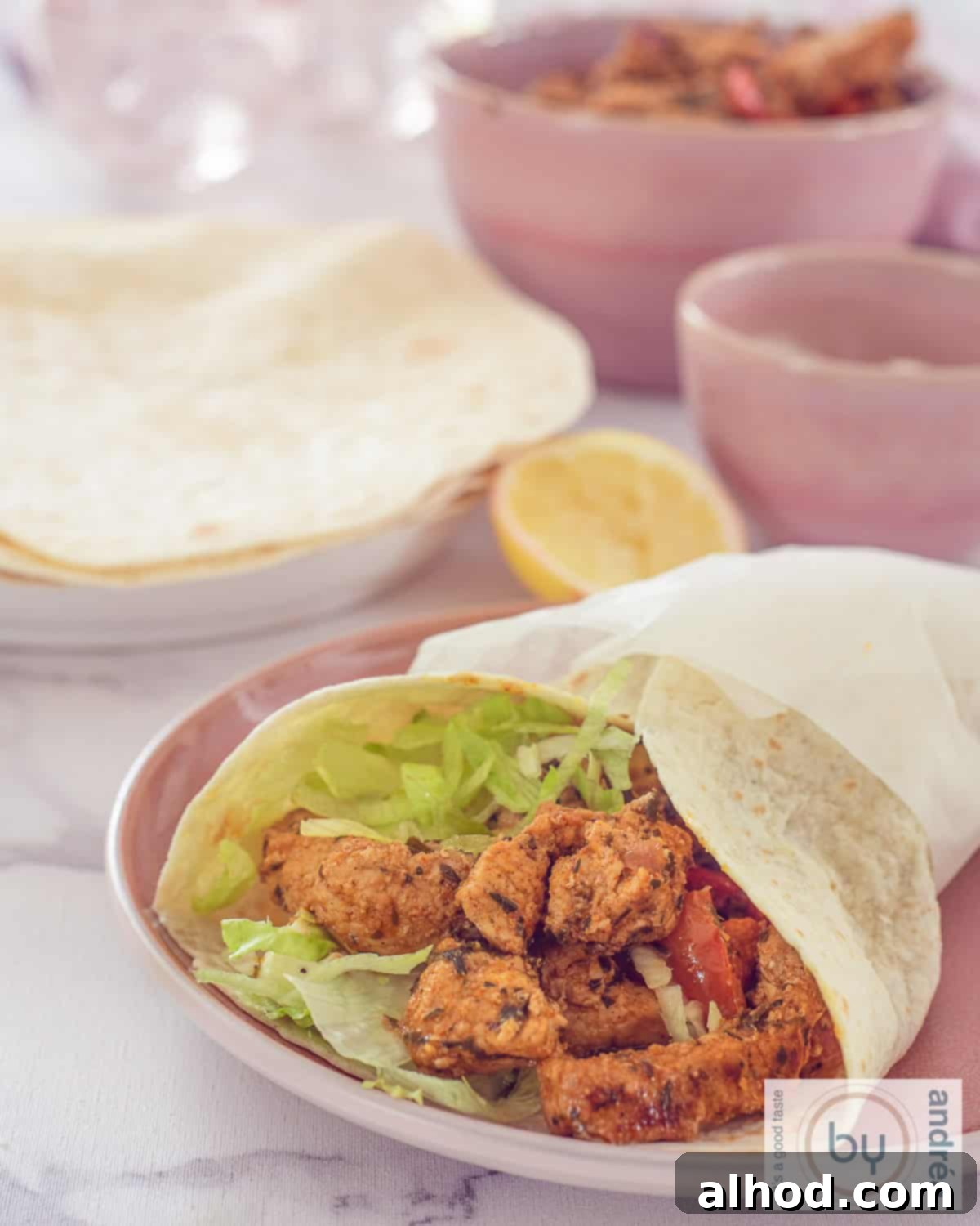15-Minute Fresh Gyros Wraps 3 A height photo: a wrap filled with gyros meat and lettuce. In the background, wraps and bowls with side dishes.